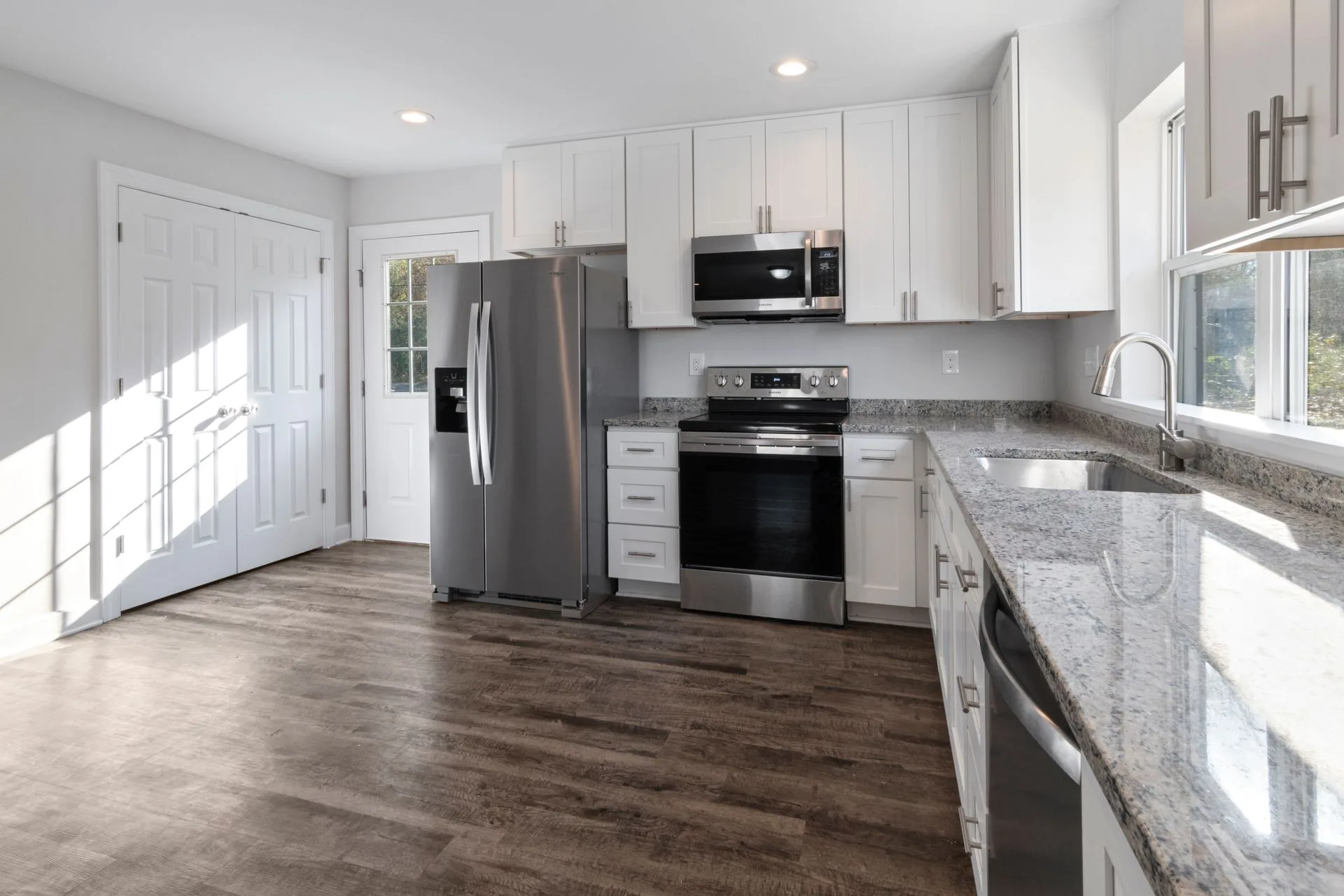 Newly installed kitchen with white cabinets, granite benchtops and stainless steel appliances